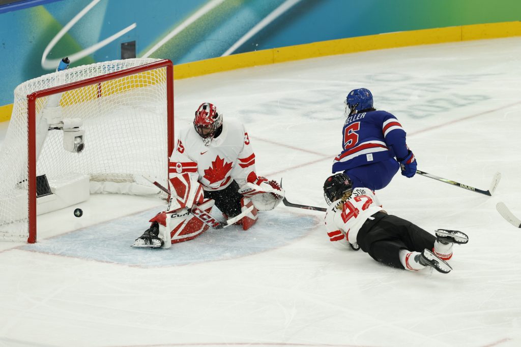 Feb 19, 2026; Milan, Italy; Megan Keller (5) of the United States scoring the game winning goal against Ann-Renee Desbiens (35) of Canada in overtime of the women's ice hockey gold medal game during the Milano Cortina 2026 Olympic Winter Games at Milano Santagiulia Ice Hockey Arena.