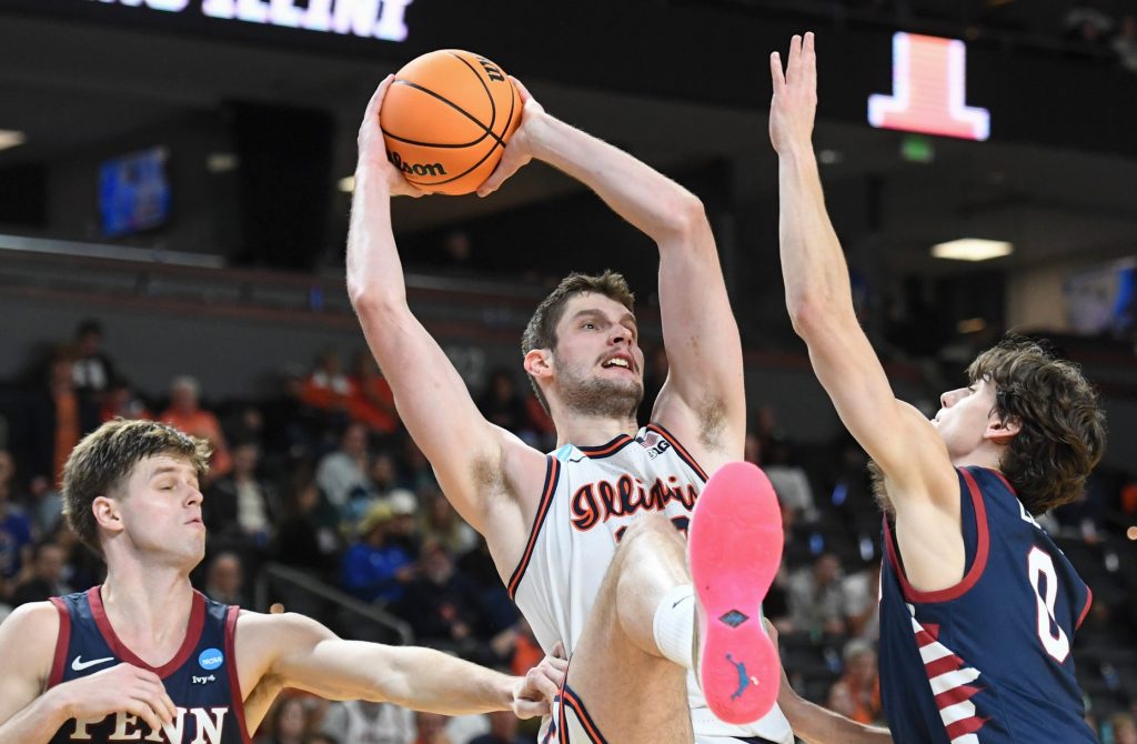 Penn Quakers guard Michael Zanoni (7) and Penn Quakers guard AJ Levine (0) defend Illinois Fighting Illini center Tomislav Ivisic (13) Thursday, March 19, 2026, during the NCAA Men’s Basketball Tournament first round game at Bon Secours Wellness Arena in Greenville, South Carolina. Illinois Fighting Illini won 105-70.