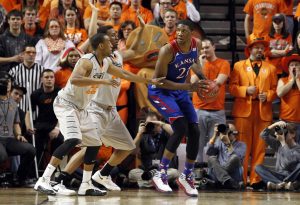 Mar 1, 2014; Stillwater, OK, USA; Kansas Jayhawks center Joel Embiid (21) is defended by Oklahoma State Cowboys forward/center Kamari Murphy (21) and guard Markel Brown (22) during the first half at Gallagher-Iba Arena.