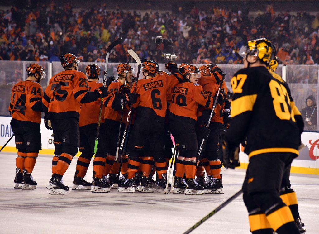 Feb 23, 2019; Philadelphia, PA, USA; The Philadelphia Flyers celebrate the game-winning goal by center Claude Giroux (not pictured) as Pittsburgh Penguins center Sidney Crosby (87) skates by in a Stadium Series ice hockey game at Lincoln Financial Field.
