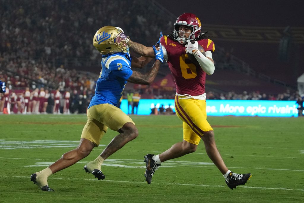 Nov 29, 2025; Los Angeles, California, USA; Southern California Trojans wide receiver Makai Lemon (6) carries the ball against UCLA Bruins defensive back Andre Jordan Jr. (2) in the second half at United Airlines Field at Los Angeles Memorial Coliseum.