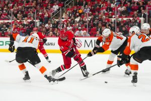 Dec 14, 2025; Raleigh, North Carolina, USA; Carolina Hurricanes center Seth Jarvis (24) takes a shot against Philadelphia Flyers center Rodrigo Abols (18) and right wing Travis Konecny (11) during the first period at Lenovo Center.