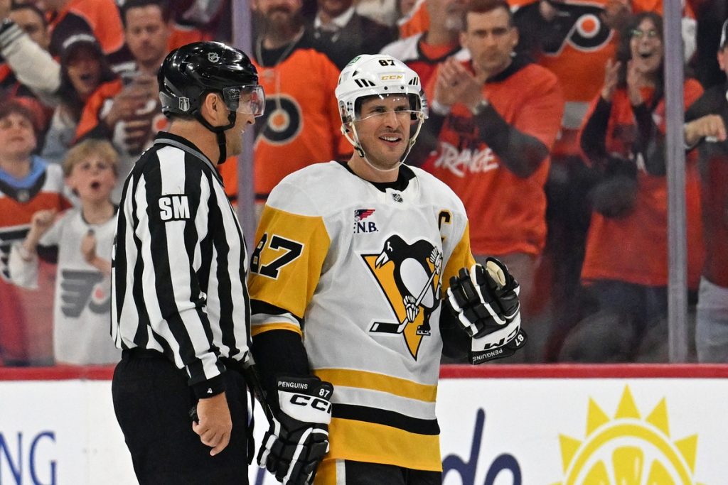 Apr 22, 2026; Philadelphia, Pennsylvania, USA; Pittsburgh Penguins center Sidney Crosby (87) is escorted to the penalty box by linesman Jonny Murray (95) against the Philadelphia Flyers during the second period in game three of the first round of the 2026 Stanley Cup Playoffs at Xfinity Mobile Arena.