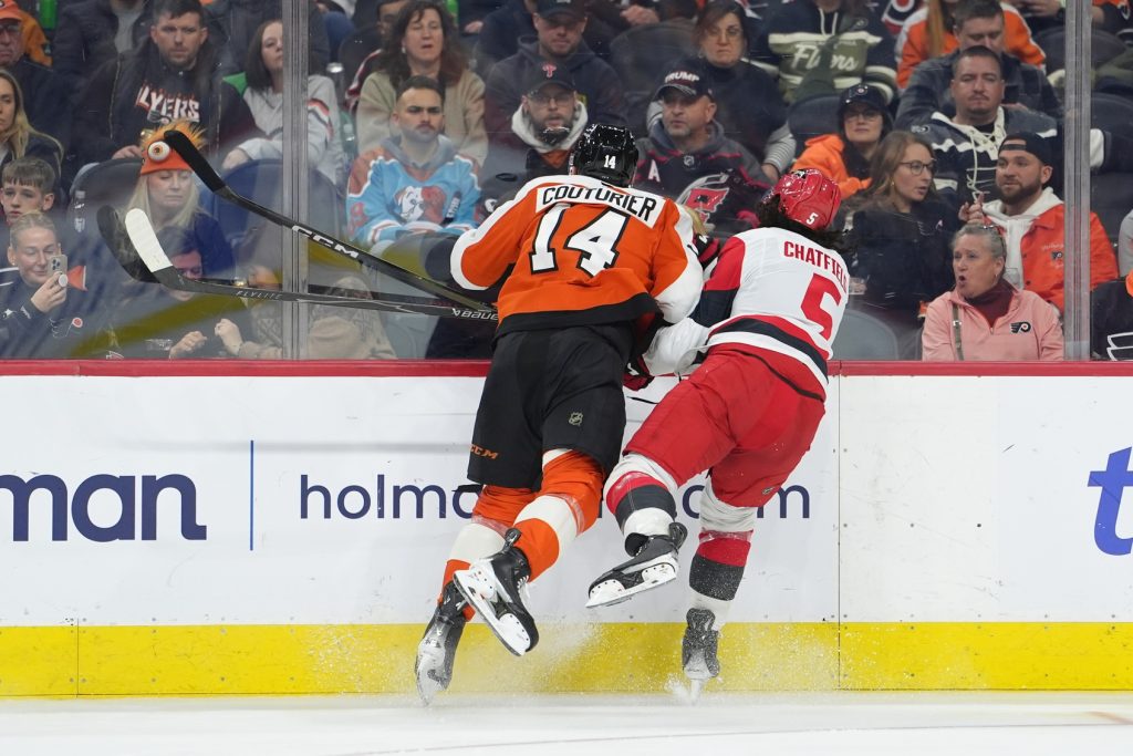 Dec 13, 2025; Philadelphia, Pennsylvania, USA; Philadelphia Flyers center Sean Couturier (14) hits Carolina Hurricanes defenseman Jalen Chatfield (5) in the second period at Xfinity Mobile Arena.