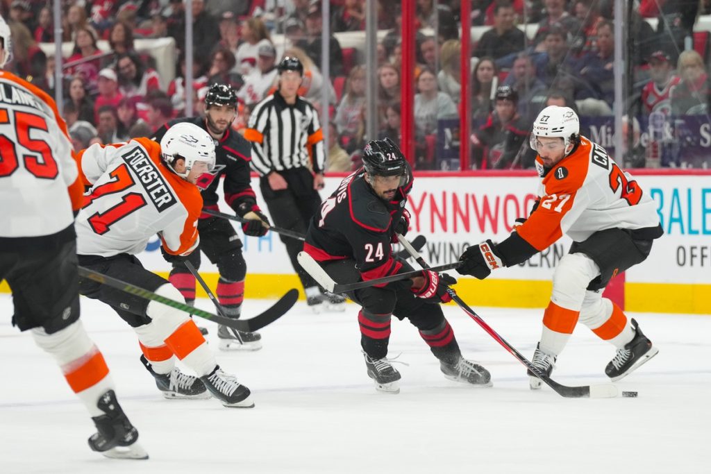 May 2, 2026; Raleigh, North Carolina, USA; Carolina Hurricanes center Seth Jarvis (24) skates with the puck between Philadelphia Flyers left wing Noah Cates (27) and right wing Tyson Foerster (71) during the third period at Lenovo Center.