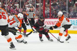 May 2, 2026; Raleigh, North Carolina, USA; Carolina Hurricanes center Seth Jarvis (24) skates with the puck between Philadelphia Flyers left wing Noah Cates (27) and right wing Tyson Foerster (71) during the third period at Lenovo Center.