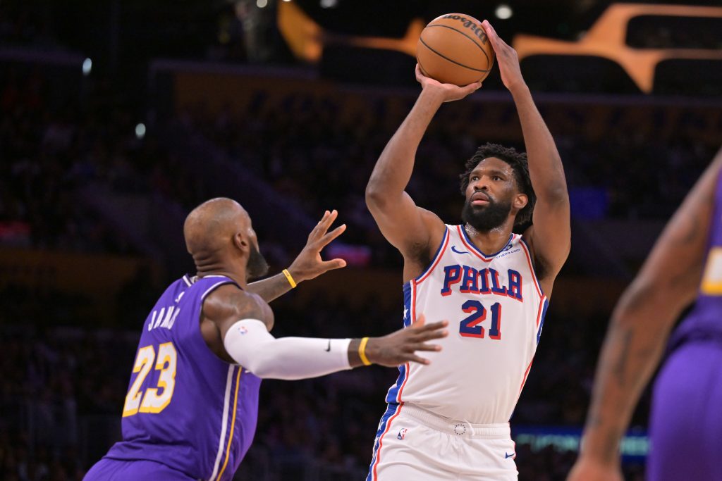 Feb 5, 2026; Los Angeles, California, USA; Philadelphia 76ers center Joel Embiid (21) shoots over Los Angeles Lakers forward LeBron James (23) in the first half at Crypto.com Arena.