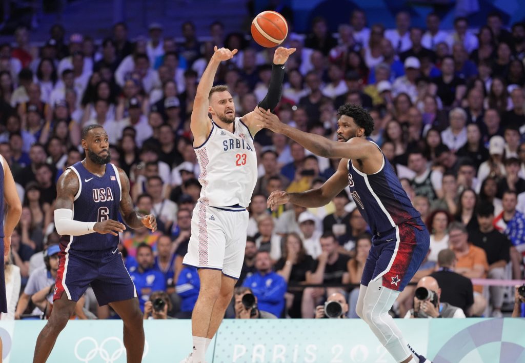 Jul 28, 2024; Villeneuve-d'Ascq, France; Serbia shooting guard Marko Guduric (23) passes against United States guard Lebron James (6) and center Joel Embiid (11) in the second quarter against Serbia during the Paris 2024 Olympic Summer Games at Stade Pierre-Mauroy.