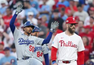 Oct 6, 2025; Philadelphia, Pennsylvania, USA; Los Angeles Dodgers shortstop Mookie Betts (50) celebrates a single as Philadelphia Phillies first baseman Bryce Harper (3) looks on in the first inning during game two of the NLDS round for the 2025 MLB playoffs at Citizens Bank Park.