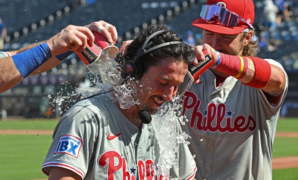 Aug 25, 2024; Kansas City, Missouri, USA; Philadelphia Phillies catcher Garrett Stubbs (21) receives a victory shower from teammates Bryson Stott (5) and Brandon Marsh (16) after beating the Kansas City Royals at Kauffman Stadium.