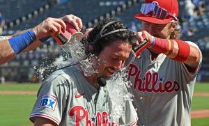 Aug 25, 2024; Kansas City, Missouri, USA; Philadelphia Phillies catcher Garrett Stubbs (21) receives a victory shower from teammates Bryson Stott (5) and Brandon Marsh (16) after beating the Kansas City Royals at Kauffman Stadium.