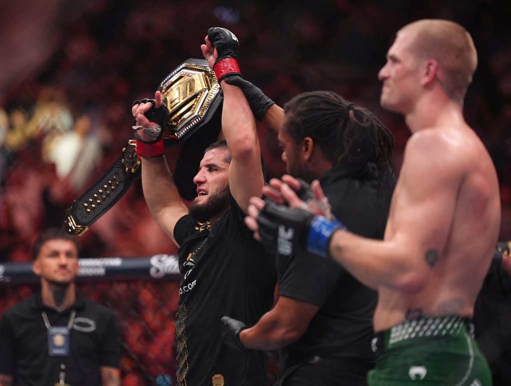 Aug 15, 2026; Philadelphia, Pennsylvania, USA; Islam Makhachev (red gloves) celebrates after defeating Iah Machado Garry (blue gloves) in the welterweight title bout during UFC 330 at Xfinity Mobile Arena.