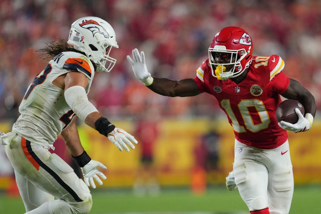 Sep 14, 2026; Kansas City, Missouri, USA; Kansas City Chiefs running back Emmett Johnson (10) rushes the ball against Denver Broncos linebacker Alex Singleton (49) at GEHA Field at Arrowhead Stadium.