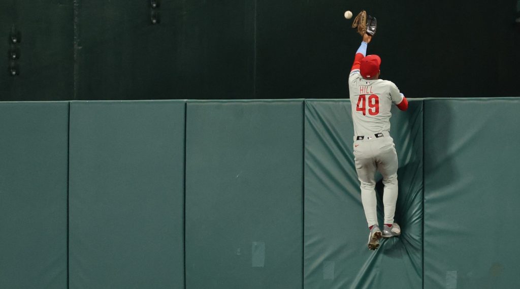 Sep 15, 2026; Washington, District of Columbia, USA; Philadelphia Phillies center fielder Derek Hill (49) scales the wall in an attempt to catch a three run go-ahead home run hit by Washington Nationals left fielder Daylen Lile (not pictured) during the seventh inning at Nationals Park.