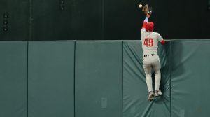 Sep 15, 2026; Washington, District of Columbia, USA; Philadelphia Phillies center fielder Derek Hill (49) scales the wall in an attempt to catch a three run go-ahead home run hit by Washington Nationals left fielder Daylen Lile (not pictured) during the seventh inning at Nationals Park.