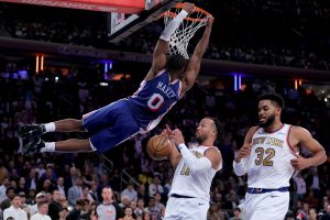 Oct 20, 2026; New York, New York, USA; Philadelphia 76ers guard Tyrese Maxey (0) hangs on the rim after a dunk against New York Knicks guard Jalen Brunson (11) and center Karl-Anthony Towns (32) during the fourth quarter at Madison Square Garden. Mandatory Credit: